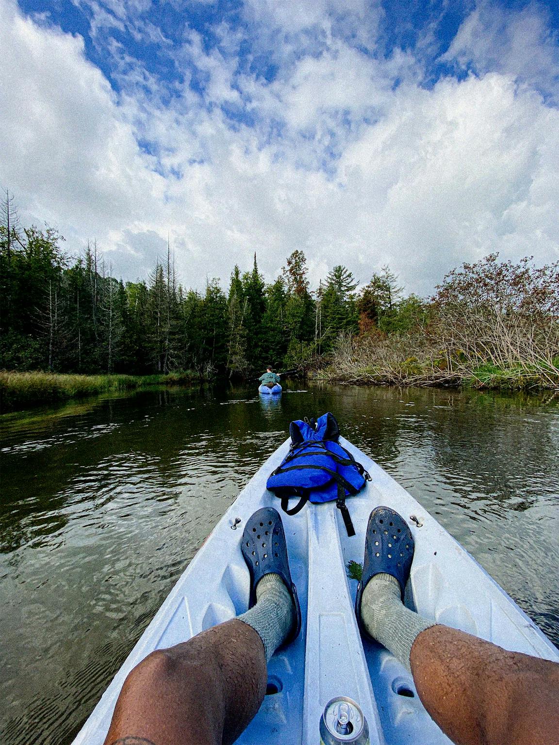 A view of a person's legs in a kayak. They're wearing blue Crocs.